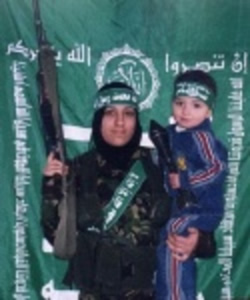Female suicide bomber holding a child and a rifle; the child is holding a rocket-propelled grenade.
