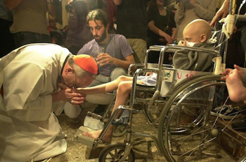 Pope Francis kisses foot of boy in a wheelchair.